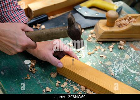 Zimmermann hämmerte einen Nagel in die Holzdiele. DIY, Holzbearbeitung Konzept. Stockfoto