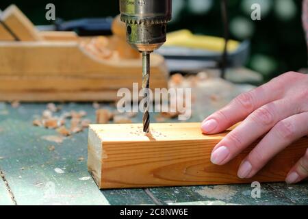 Handwerker Tischler Bohren eines Holzbohrung mit Bohrmaschine, Nahaufnahme. Holzbearbeitung, DIY-Konzept. Stockfoto