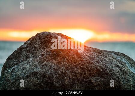 Die Sonne untergeht hinter einem Felsen am Strand der deutschen Insel Poel Stockfoto