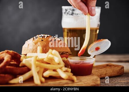 Verschiedene Arten von Fastfood und Snacks und ein Glas Bier auf dem Tisch. Ungesunde und Junk-Food. Stockfoto