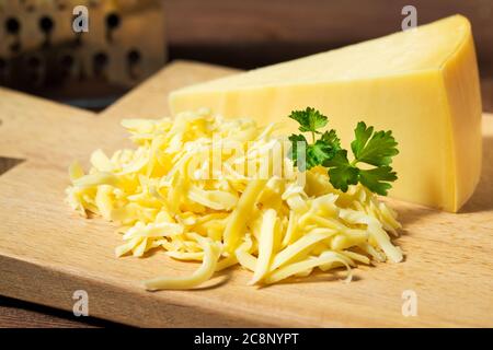 Geriebener Käse und Käse Dreieck auf Holz Schneidebrett Stockfoto