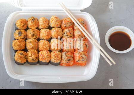 Setzen Sie japanisches Sushi mit Sojasauce und Essstäbchen auf einen grauen Betonboden. Lieferung von Speisen im Restaurant. Draufsicht. Stockfoto