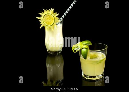 CAIPIRINHA ZITRONE MIT CHAMPAGNER EIN BRASILIANISCHES GETRÄNK IN SCHWARZEM HINTERGRUND FOTOGRAFIERT Stockfoto