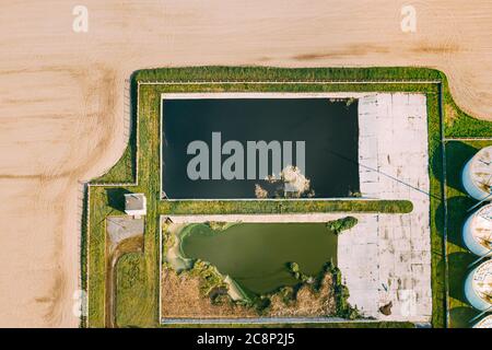 Luftaufnahme von Retentionsbecken, Feuchtteich, Nassgefängnisbecken oder Sturmwasserbewirtschaftungsbecken in der Nähe der Biogas-Biogasanlage von der Schweinegastanlage. Künstlicher Teich Stockfoto