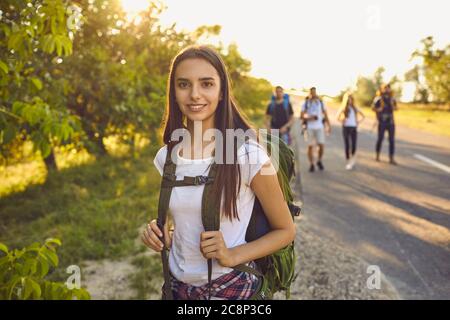 Wanderer Mädchen mit einem Rucksack lächelt auf einem Ausflug in einer Reise in die Natur. Wandertourismus