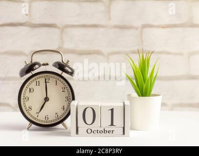 1. Oktober auf dem Holzkalender neben dem Wecker, das Datum des Herbstmonats. Stockfoto