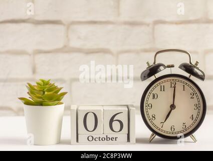 6. Oktober auf dem Holzkalender neben dem Wecker, das Datum des Herbstmonats. Stockfoto