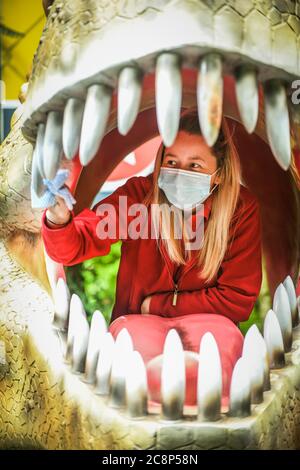 26. Juli 2020, Brecon Beacons, Wales. Mitarbeiter Elisha Lewis reinigt das Innere eines Dinosauriermaul in Dan-yr-Ogof Caves in Wales. Die Attraktion, die den größten Höhlenkomplex ihrer Art in Großbritannien hat und sich im Brecon Beacons National Park befindet, hat dieses Wochenende nach monatelanger Schließung aufgrund der Coronavirus-Sperre wieder eröffnet. Ähnliche Attraktionen in England, die seit einem Monat geöffnet sind, drängten die walisische Regierung, diesem Beispiel zu folgen und Dan-yr-Ogof ihre Türen öffnen zu lassen. Kredit : Robert Melen/Alamy Live Nachrichten. Stockfoto