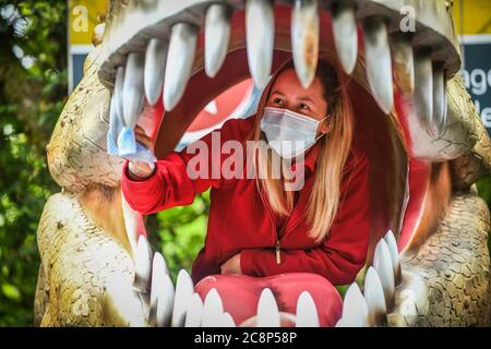 26. Juli 2020, Brecon Beacons, Wales. Mitarbeiter Elisha Lewis reinigt das Innere eines Dinosauriermaul in Dan-yr-Ogof Caves in Wales. Die Attraktion, die den größten Höhlenkomplex ihrer Art in Großbritannien hat und sich im Brecon Beacons National Park befindet, hat dieses Wochenende nach monatelanger Schließung aufgrund der Coronavirus-Sperre wieder eröffnet. Ähnliche Attraktionen in England, die seit einem Monat geöffnet sind, drängten die walisische Regierung, diesem Beispiel zu folgen und Dan-yr-Ogof ihre Türen öffnen zu lassen. Kredit : Robert Melen/Alamy Live Nachrichten. Stockfoto