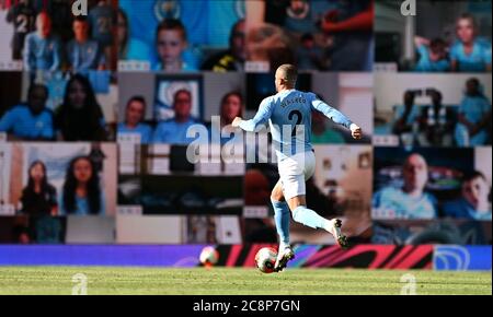 Kyle Walker von Manchester Cit läuft auf die Fans zu, die während des Premier League-Spiels im Etihad Stadium in Manchester vom riesigen Bildschirm aus zusehen. Stockfoto