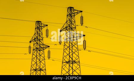 Elektroindustrie. Sendetürme oder Elektrizitätspylone mit goldenem Himmel Stockfoto