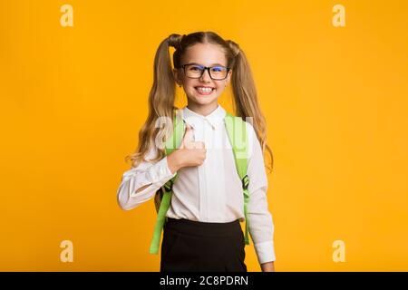 Glücklich Mädchen Gestik Thumbs-Up Bereit Für Die Schule Über Gelben Hintergrund Stockfoto