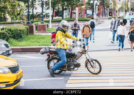 MOSKAU, RUSSLAND 7. JULI 2017: Junger Mann mit Helm und gelber Jacke sitzt auf einem Motorrad auf einem Fußgänger und wartet auf ein grünes Licht Stockfoto