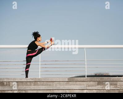 Sport Style, Workout und Übungen. Fitness african american Mädchen in Uniform tun Stretching Beine Stockfoto