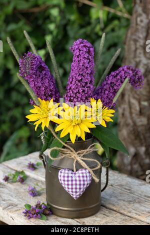 Bouquet von lila Schmetterling Buschblumen, Rudbeckia und Gräser in Jahrgangsmilch kann Stockfoto