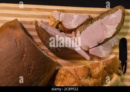 Schinken in Scheiben auf Holzschneidebrett. Frischer Schinken. Stockfoto