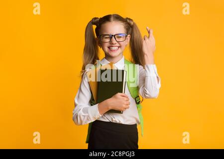 Schulmädchen Halten Die Daumen Gedrückt Für Glück In Der Schule, Studio Shot Stockfoto