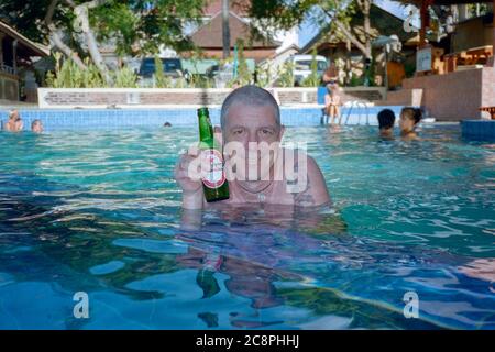 westliche kaukasische Touristen lächeln, während sie eine Flasche des lokalen Bieres bintang im Hotelschwimmbad kuta bali indonesia 2002 halten Stockfoto