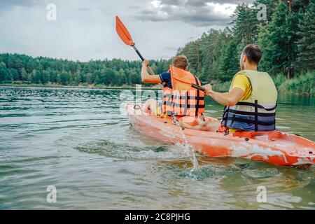 Zwei Jungs in einem roten Kajak auf dem Fluss, in Schwimmwesten Stockfoto