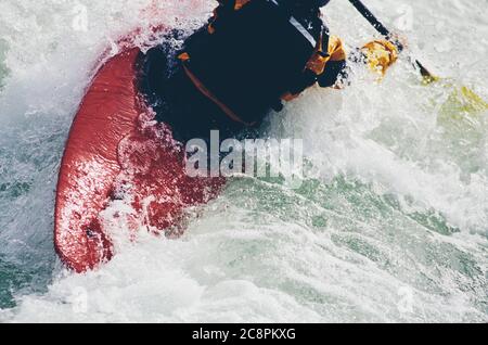 Wildwasser-Kajakfahrerin paddelt Stromschnellen und surft auf einem schnell fließenden Fluss. Stockfoto