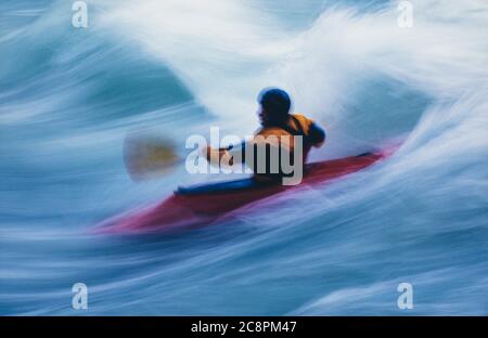 Lange Exposition der männlichen Wildwasser-Kajakfahrer paddeln und Surfen großen Stromschnellen auf einem schnell fließenden Fluss. Stockfoto