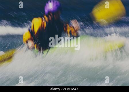 Lange Exposition von weiblichen Wildwasser Kajakfahrer paddeln Stromschnellen und surfen auf einem schnell fließenden Fluss. Stockfoto