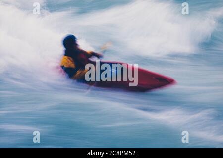 Lange Exposition der männlichen Wildwasser-Kajakfahrer paddeln und Surfen großen Stromschnellen auf einem schnell fließenden Fluss. Stockfoto