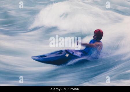 Lange Exposition der männlichen Wildwasser-Kajakfahrer paddeln und Surfen großen Stromschnellen auf einem schnell fließenden Fluss. Stockfoto