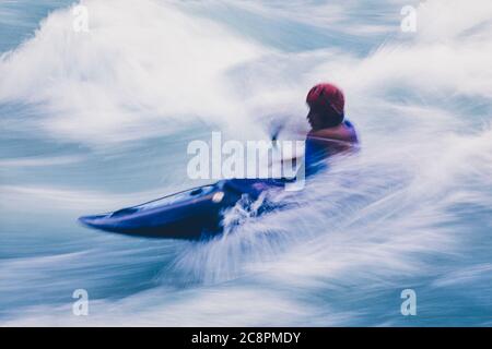 Lange Exposition der männlichen Wildwasser-Kajakfahrer paddeln und Surfen großen Stromschnellen auf einem schnell fließenden Fluss. Stockfoto