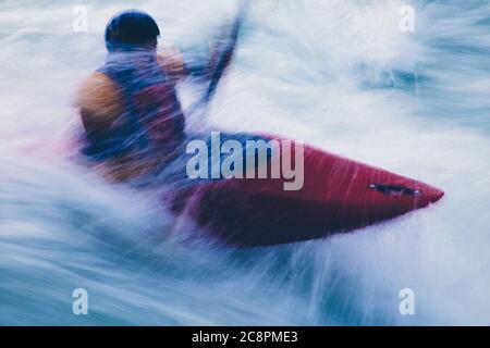 Lange Exposition der männlichen Wildwasser-Kajakfahrer paddeln und Surfen großen Stromschnellen auf einem schnell fließenden Fluss. Stockfoto