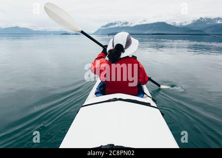 Eine Frau mittleren Alters paddelt Seekajak in den unberührten Gewässern von Muir Inlet, Glacier Bay National Park und Preserve, Alaska Stockfoto