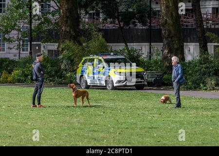 Polizei in einem Polizeifahrzeug auf Patrouille in einem Londoner Park, um soziale Distanzierungsmaßnahmen durchzusetzen. Stockfoto