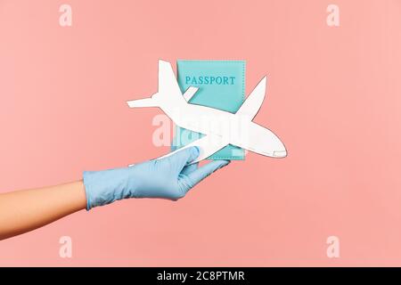 Profil Seitenansicht Nahaufnahme der menschlichen Hand in blauen OP-Handschuhe halten Pass und Flugzeug Papier. Indoor, Studio-Aufnahme, isoliert auf rosa Hintergrund. Stockfoto