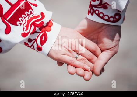 Brautpaare halten die Hände in roter Stickerei Stockfoto