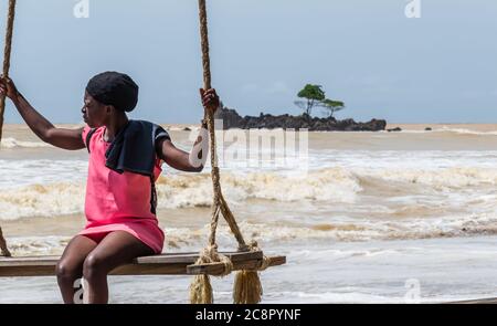 Afrikanische Frau sitzt am Meer auf einem Hängesessel. Axim Ghana Westafrika Strand Stockfoto