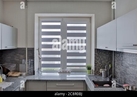 Moderne graue Küche verfügt über graue flache Front Schränke gepaart mit grauen Arbeitsplatten und einem glänzenden grauen linearen Fliesen backsplash. Stockfoto