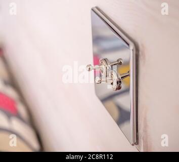 Verchromte Knebelschalter im Retro-Stil, die am Kopfteil aus Holz im Schlafzimmer angebracht sind. Stockfoto