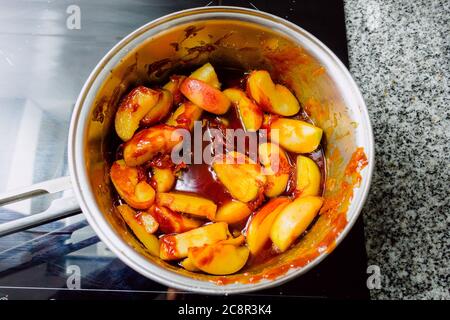 Luftaufnahme von karamellisierten Äpfeln in einem Topf auf einem Induktionsherd bereit, einen Apfelkuchen vorzubereiten Stockfoto