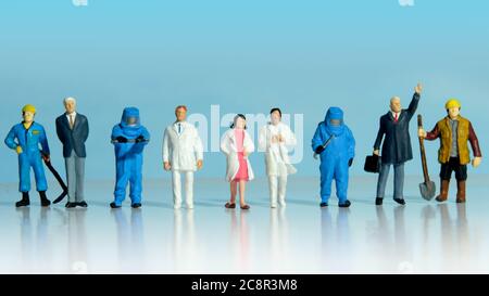 Gruppe von Männern in verschiedenen Beruf Schlange sich mit Ärzten und Krankenschwestern Unterstützung sie zu kämpfen zusammen. Miniatur Menschen konzeptuelle Fotografie. Stockfoto