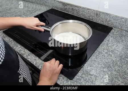 Die weibliche Hand schaltet die Nahaufnahme des elektrischen Kochfelds ein. Prozess Machen Sie einen Apfelkuchen Stockfoto