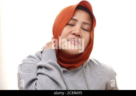 Asiatische muslimische Frau trägt Hijab mit Nackenschmerzen. Nahaufnahme Porträt isoliert auf weiß Stockfoto