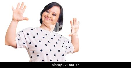 Brunette Frau mit Down-Syndrom tragen lässige Kleidung zeigt und zeigt mit den Fingern Zahl zehn, während lächelnd zuversichtlich und glücklich. Stockfoto