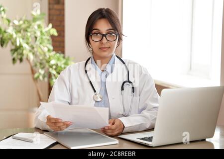 Selbstbewusst indischen Arzt tragen weißen Mantel Blick auf Kamera bei der Arbeit. Stockfoto