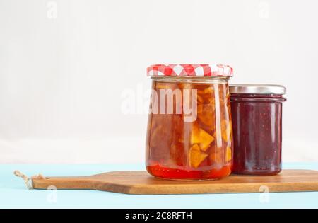 Zwei Gläser mit Apfel- und Himbeerkonfitüre auf einem Holzbrett Stockfoto