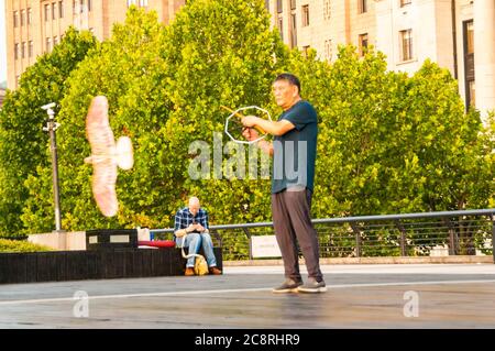 Ein Rentner fliegt am frühen Morgen einen Vogel-förmigen Drachen auf Shanghais Bund Promenade. Stockfoto