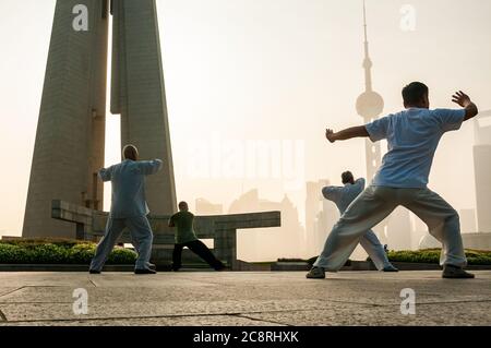 Tai Chi Übungen am Denkmal für die Helden des Volkes am Ufer des Bund von Shanghai früh am Morgen. Stockfoto