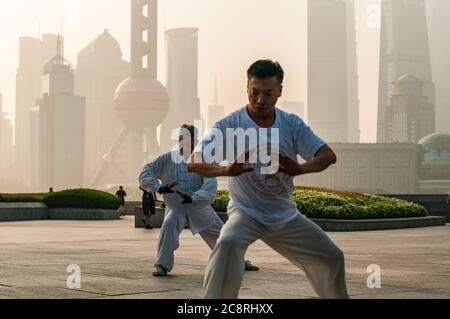 Tai Chi Übungen am Denkmal für die Helden des Volkes am Ufer des Bund von Shanghai früh am Morgen. Stockfoto