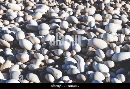 Helle weiße und graue Steine an einem sonnigen Strand Stockfoto