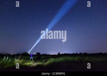 Mann mit Taschenlampe gegen erstaunliche Nacht Sternenhimmel mit Komet Stockfoto