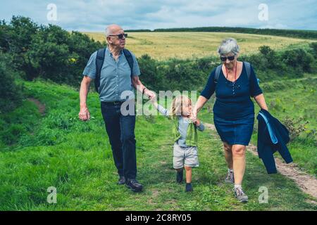 Großeltern wandern mit ihrem Vorschulenkelkind auf dem Land Stockfoto